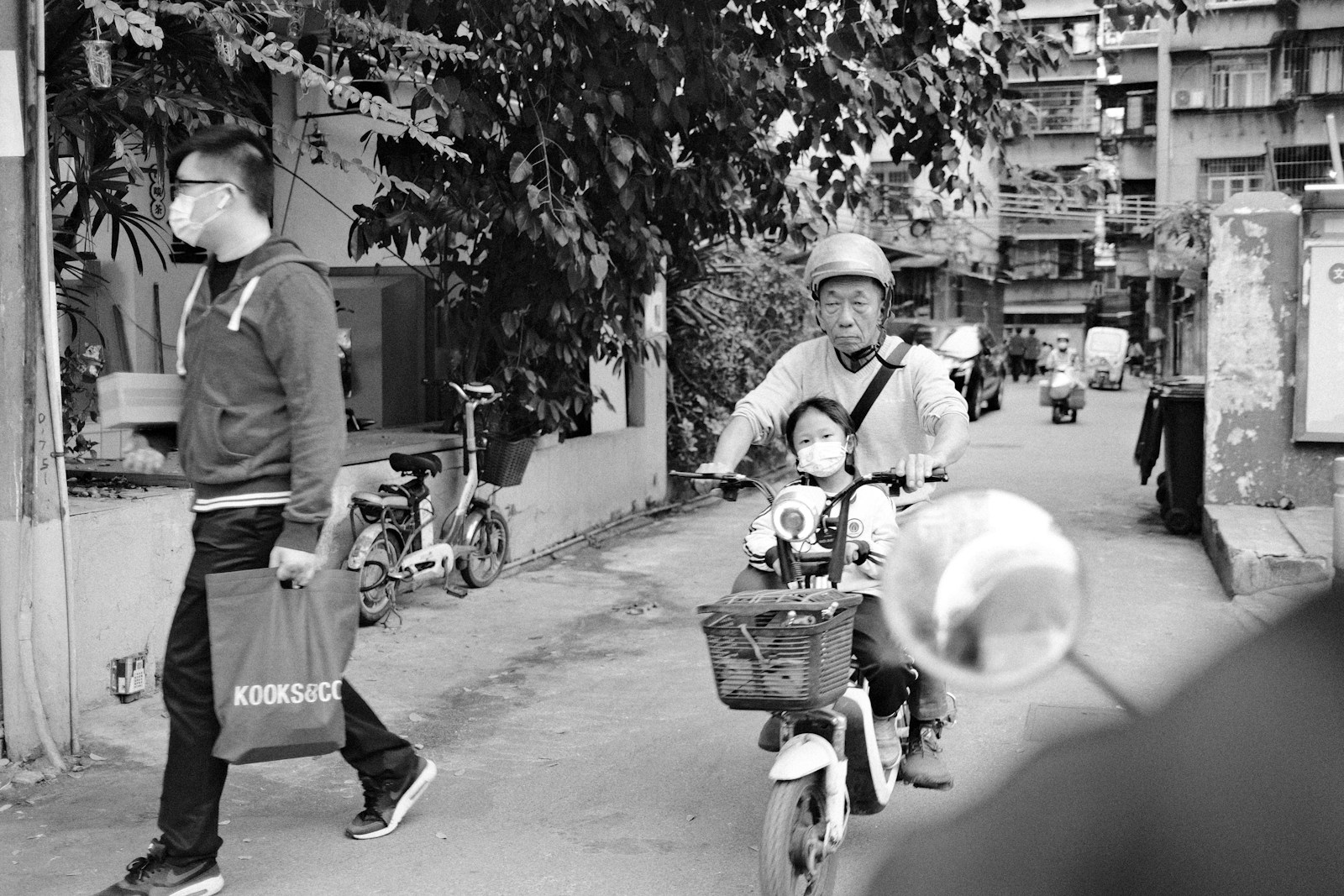 a black and white photo of a man riding a motorcycle with a child on the