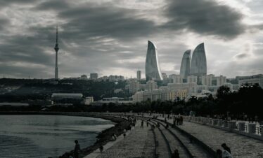 Modern city skyline with flame-shaped buildings and tower.