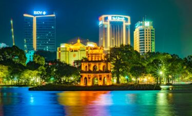 a night view of a city with a lake in front of it