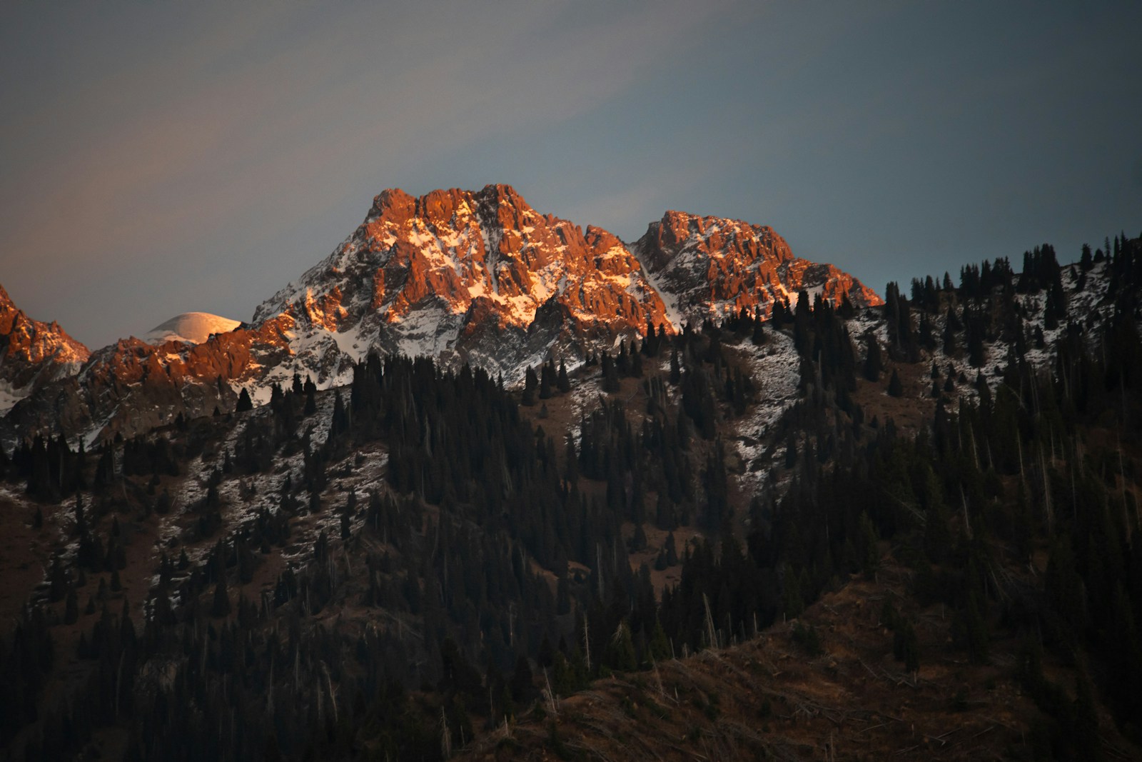 Golden sunlight illuminates snow-capped mountain peaks at sunset