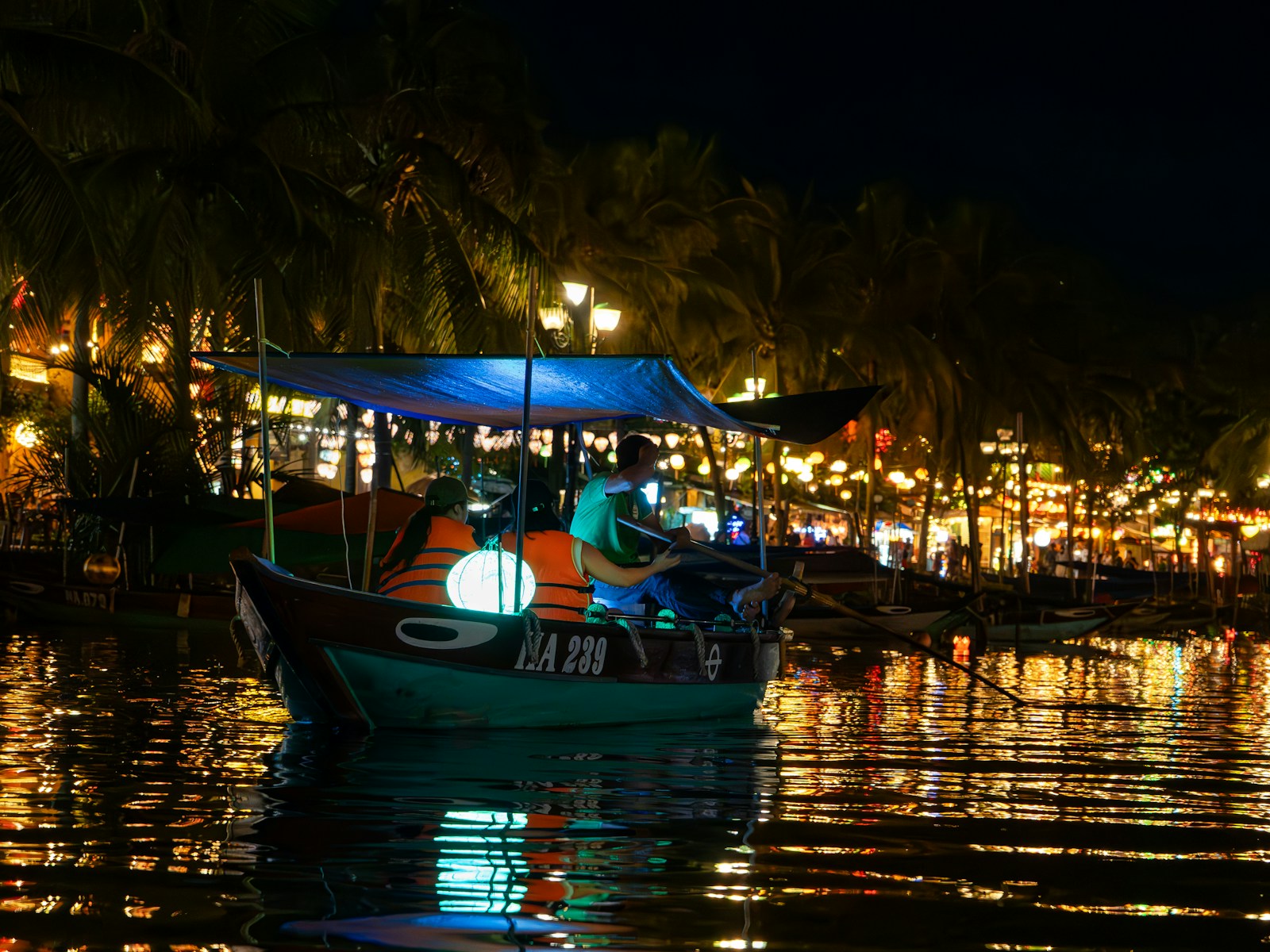 Boat with illuminated lanterns on a river at night.