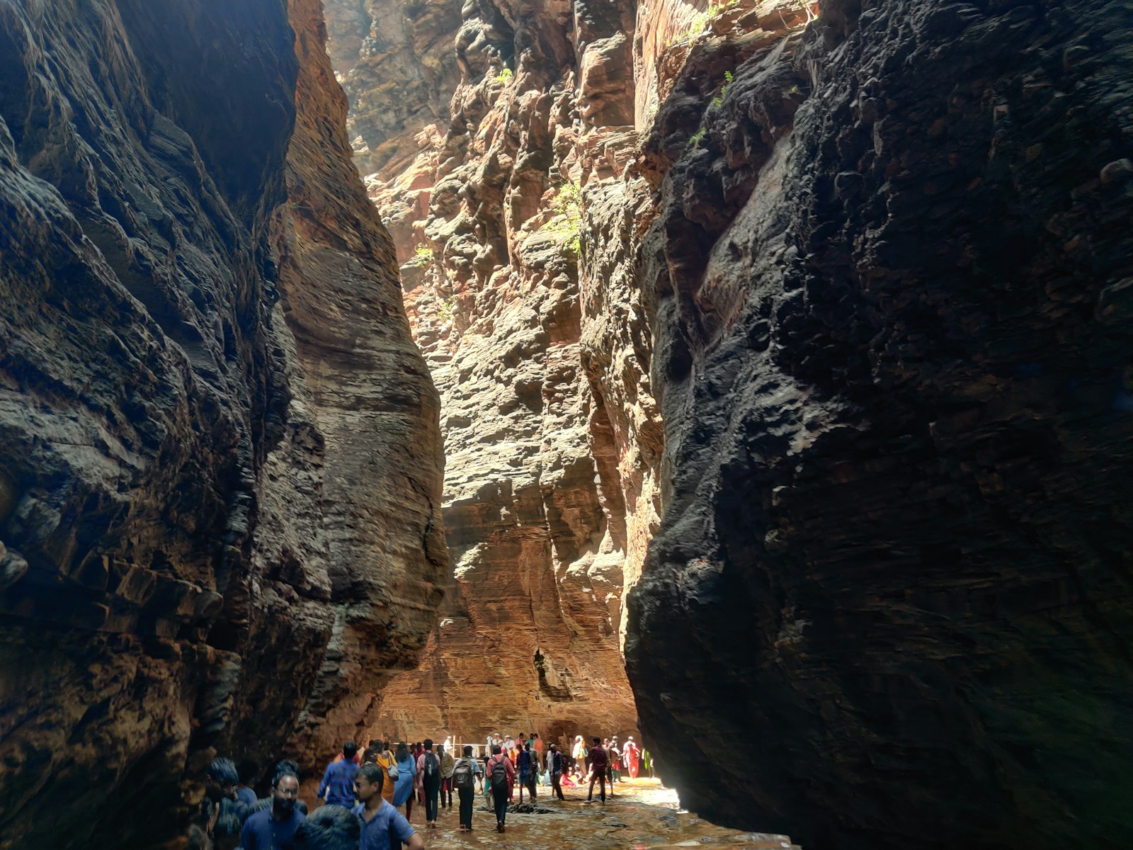 a group of people walking through a narrow canyon